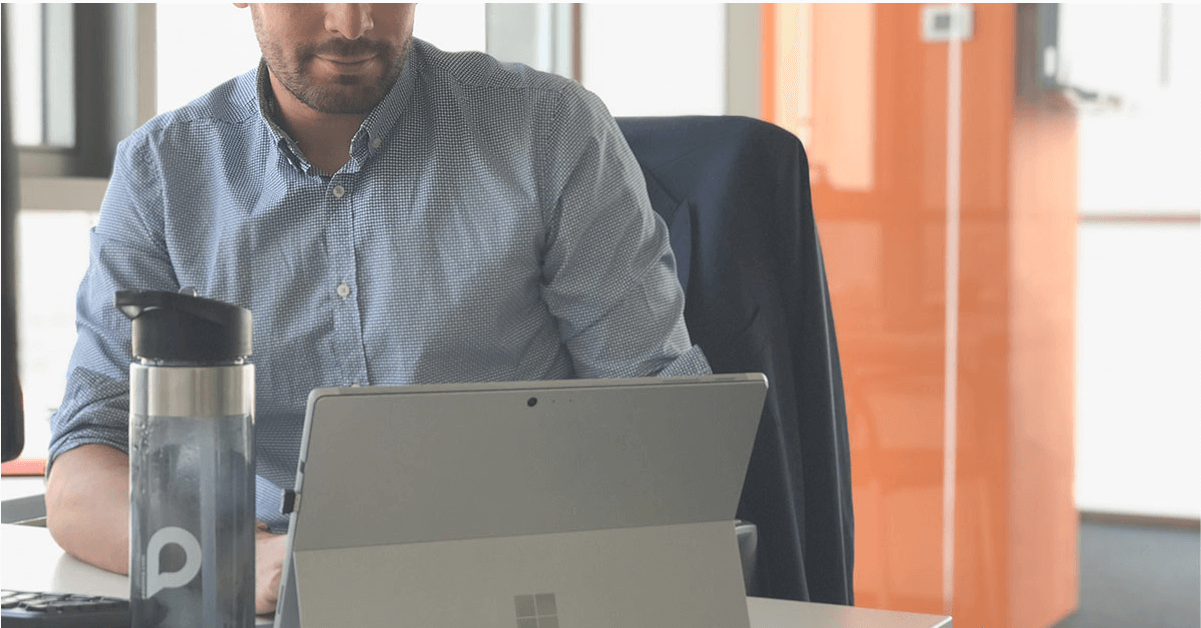 Un chico trabajando con una Surface y con una botella reutilizable de Pasiona